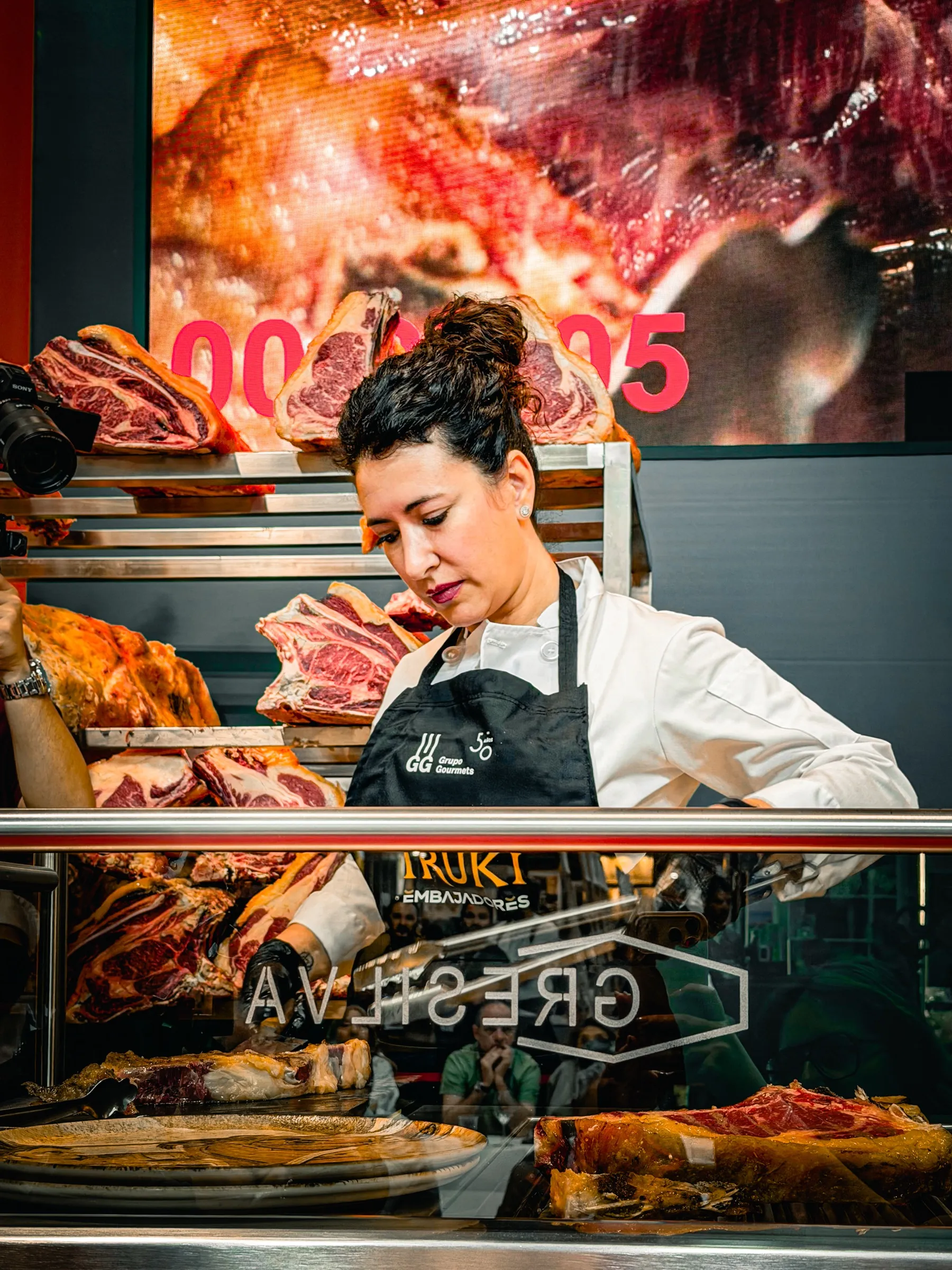Davinia Martínez concentrada en el corte de la carne, con delantal negro y chaquetilla blanca