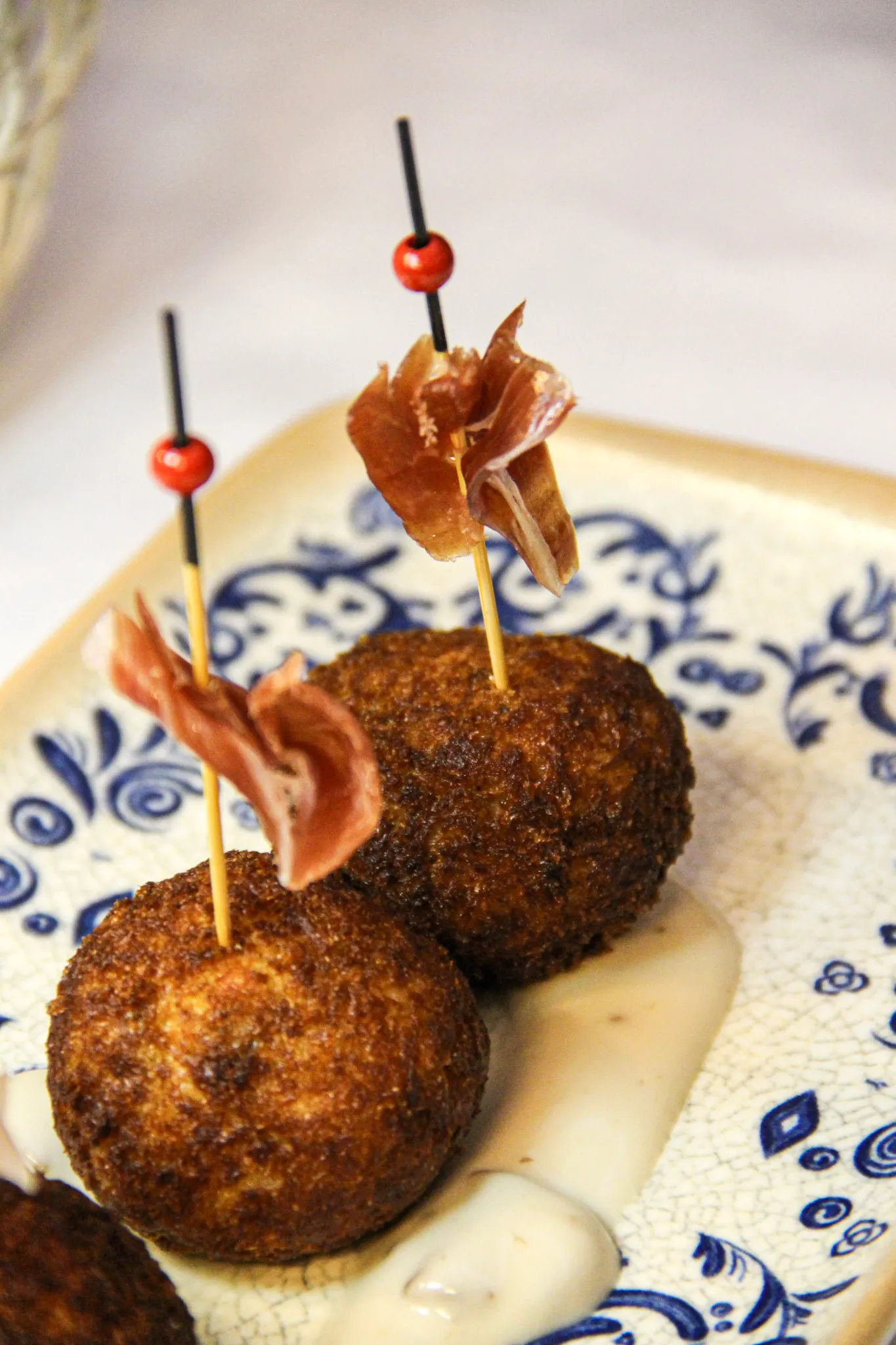Croquetas con jamón sobre loza azul y blanca