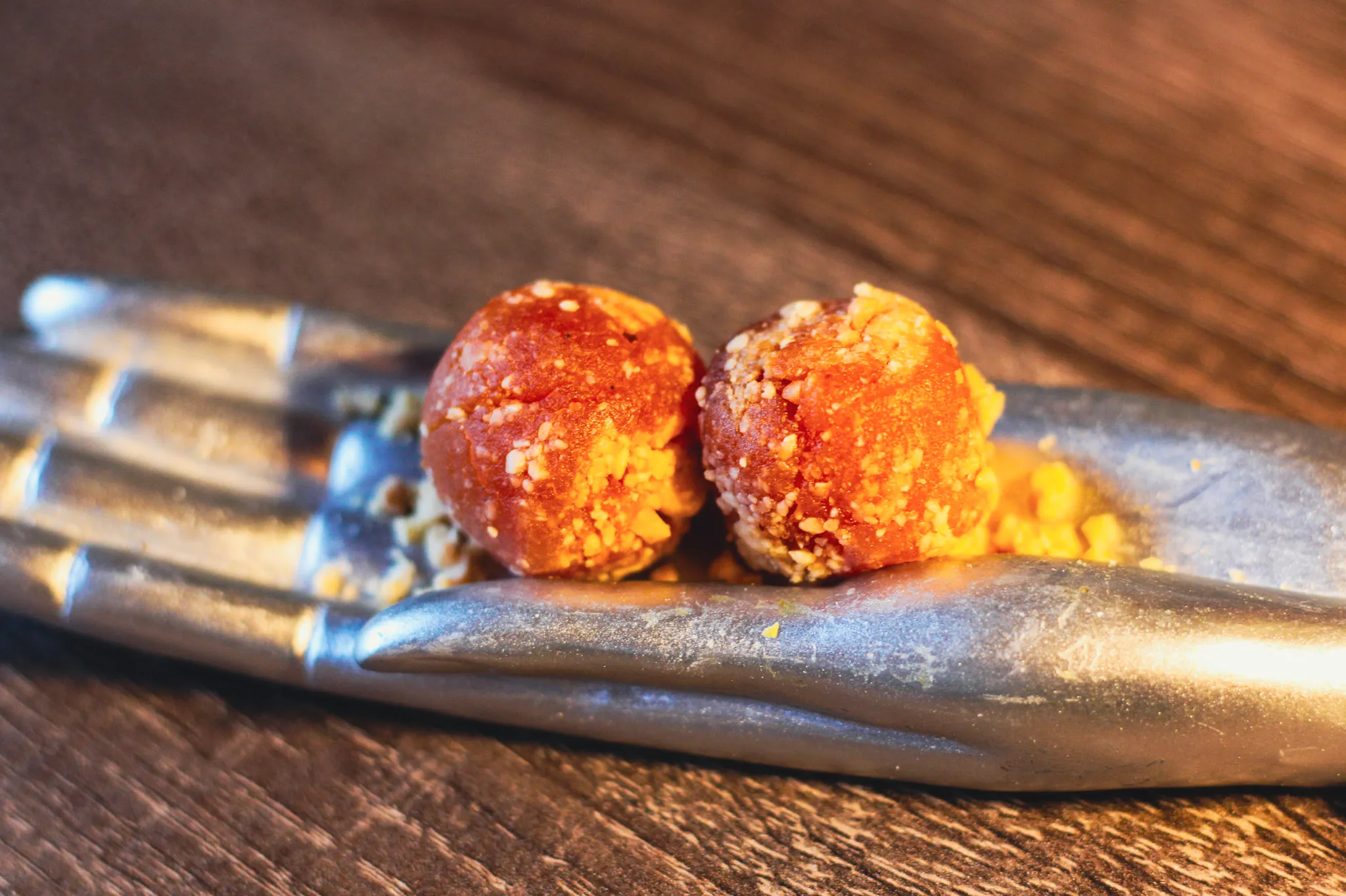 Buñuelos dorados sobre cuchara metálica y madera oscura