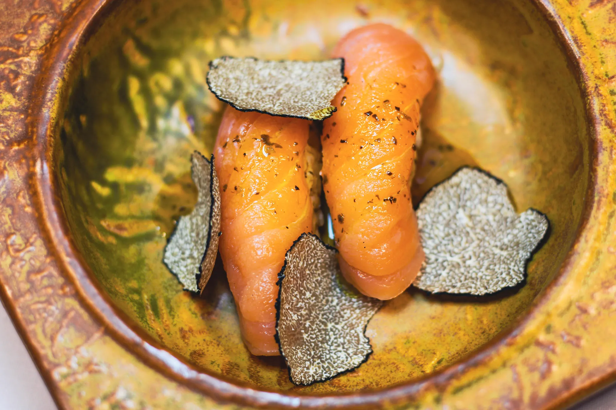 Nigiri de salmón con láminas de trufa negra en cuenco de cerámica