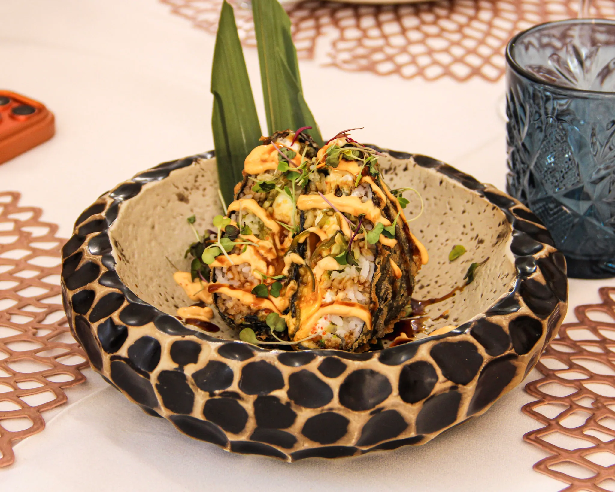 Roll de sushi en tempura con mayonesa picante y hoja de bambú